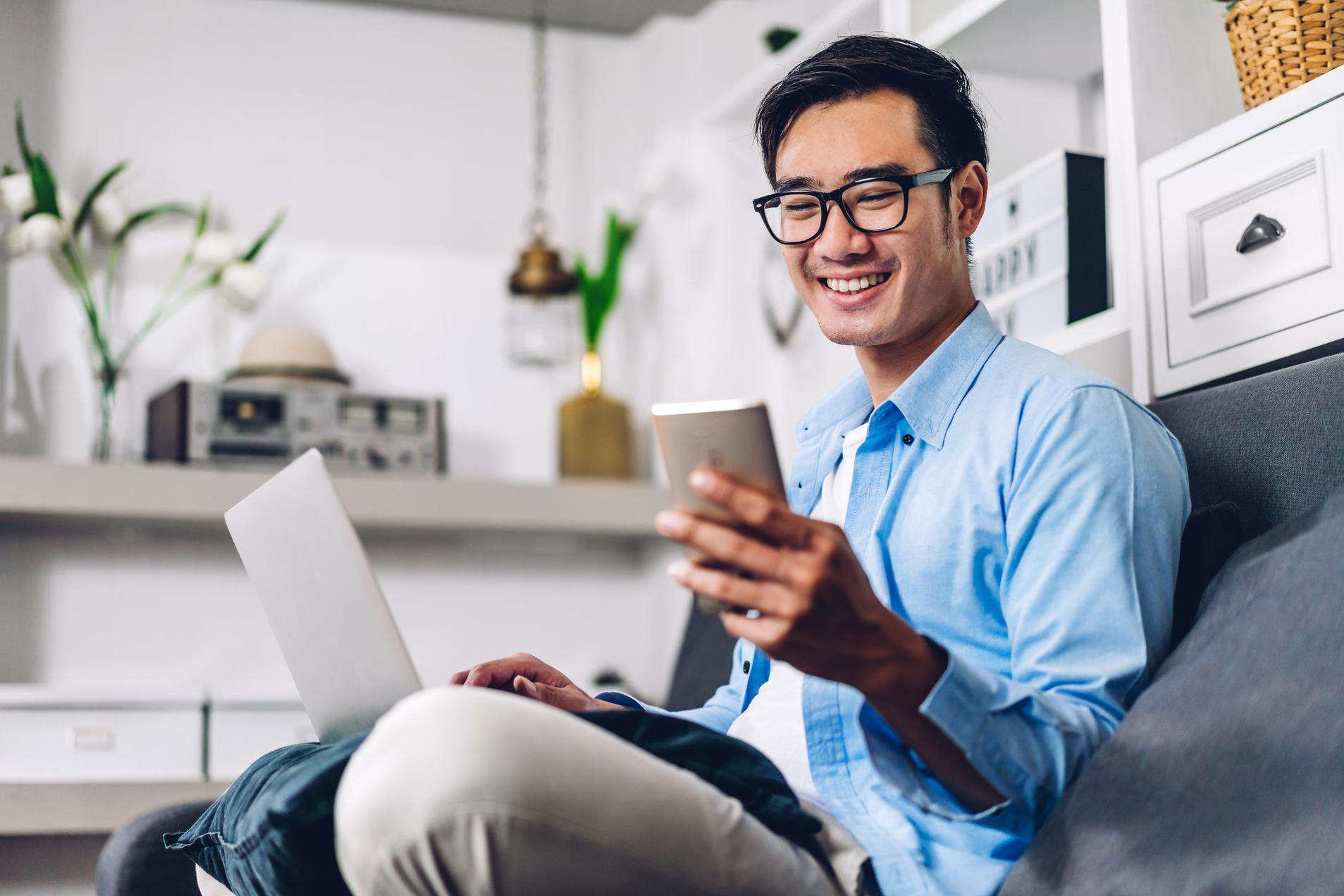 young-man-glasses-on-couch-cell-phone-computer.jpg